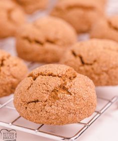 some cookies are cooling on a rack with other muffins in the back ground