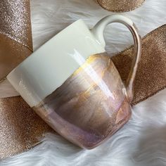 a brown and white coffee cup sitting on top of a fur covered floor next to gold glitter