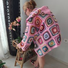 a woman standing next to a ladder with a crocheted blanket on it