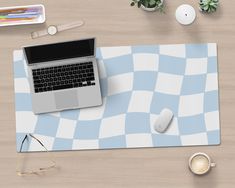 a laptop computer sitting on top of a blue and white checkered mouse pad next to a cup of coffee