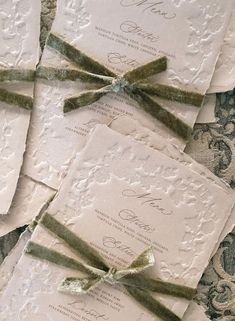 the wedding stationery is laid out on top of each other and tied with green ribbon