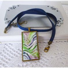 a blue lanyard with an abstract painting on it and a key chain attached to it