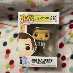 the office pop vinyl figure is in its box on a bed with polka dot sheets