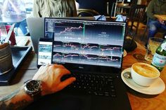 a man sitting in front of a laptop computer on top of a wooden table next to a cup of coffee