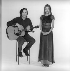 a woman sitting next to a man holding a guitar