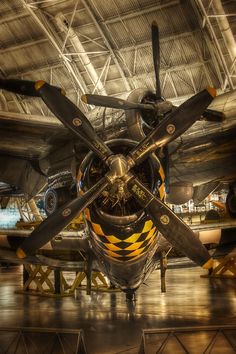 an old fashioned propeller plane sitting in a hanger