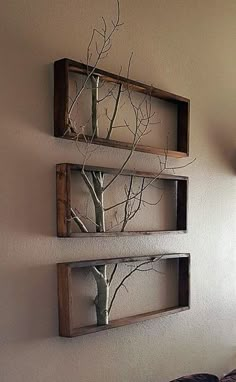 two wooden shelves with trees in them hanging on the wall next to a bed and window