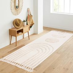 a white rug on the floor in front of a mirror and table with hat on it