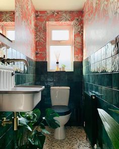 a bathroom with green and orange wallpaper, sink, toilet and window in it