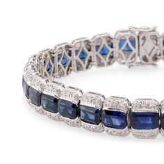 Center Stone: 29 Emerald Cut Blue SapphireWeight: 22 CaratsAccent Stone: 174 Round Brilliant Cut DiamondsWeight: 2 CaratsColor: GClarity: VSMetal: 18K White GoldEra: VintageCirca: 1990sSize: 7 1/8 inches in lengthGram weight: 24.56This stunning vintage bracelet from the 1990s is crafted in luxurious 18K white gold and features 29 vibrant emerald cut blue sapphires, totaling 22 carats. The sapphires are beautifully complemented by 174 sparkling round brilliant cut diamonds, totaling 2 carats, wit Luxury Sapphire Diamond Bracelet For Formal Occasions, Luxury Sapphire Diamond Bracelet For Formal Events, Luxury Blue Diamond Bracelet With Accents, Blue Diamond Platinum Bracelet For Formal Occasions, Formal Blue Diamond Platinum Bracelet, Luxury Blue Diamond Bracelet For Formal Occasions, Luxury Blue Diamond Bracelet For Anniversary, Luxury Blue Diamond Bracelet For Formal Events, Luxury Blue Diamond Anniversary Bracelet