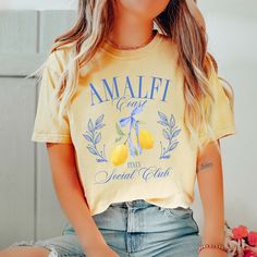 Join the club with our Amalfi Coast Social Club Tee! This tee features a stylish design that captures the essence of the Amalfi Coast. Show off your love for travel and adventure with this unique and playful tee. Guaranteed to be your go-to for your next summer outing. Design is Printed Direct to Garment. See Size Guide for Comfort Color Unisex Tee We recommend comparing these measurements against a shirt that you like the fit of for ordering a tee that will fit best. Crafted Just for You: Our products are made to order, and we're all about delivering that extra touch of personalization. Expect an order confirmation email right after you shop, and then we'll hustle to get your order ready within 7 days. When it's time to ship, we'll send you a delightfully exciting email with tracking to k Yellow T-shirt For Spring Vacation, Spring Vacation T-shirt With Crew Neck, Spring Beachy Crew Neck Top, Beachy Crew Neck Spring Tops, Beachy Crew Neck Tops For Spring, Yellow Vacation T-shirt For Spring, Yellow Spring Vacation T-shirt, Beachy Relaxed Fit T-shirt For Spring, Strawberry Mojito