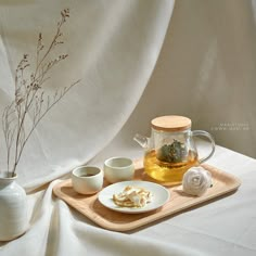 there is a tea pot and two cups on the tray