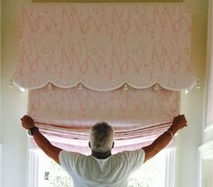 a man standing in front of a window with his hands up and arms raised above him