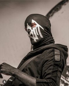 a man wearing a black and white mask holding a skateboard in his right hand