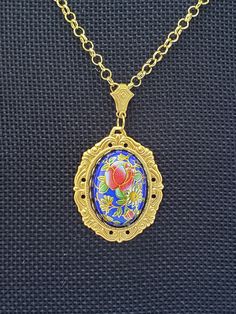 This necklace features a vintage Japanese Tensha cabochon. It has a cobalt blue background with a beautiful coral rose floral pattern, 25 x 18mm.  The base for the cabochon is a high quality, gold plated brass bezel. The cabochon pendant hangs from high quality, gold plated, rolo chain and a gold plated bail. The necklace hangs 11.5 inches from clasp to the bottom of the pendant. Traditional Gold Cabochon Necklaces, Traditional Blue Oval Pendant Necklace, Royal Gold Jewelry Gift, Royal Gold Jewelry For Gift, Royal Gold Jewelry As A Gift, Bohemian Gold Cabochon Necklace, Antique Gold Jewelry With Rose Design, Traditional Blue Cabochon Necklaces, Traditional Blue Cabochon Necklace