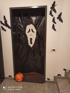 a halloween door decorated with black plastic and white ghost face, bats and pumpkins