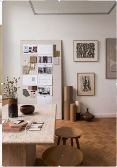 a room with wooden floors and various pictures on the wall, including vases and chairs