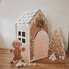 there is a gingerbread house and two trees on the floor in front of it