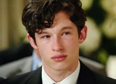 a young man in a suit and tie looking at the camera with serious expression on his face