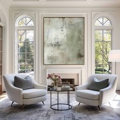 a living room with two chairs and a coffee table in front of a large painting