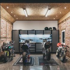 three motorcycles are parked in a garage with brick walls and ceiling lights on the ceiling