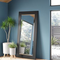 a large mirror sitting on top of a wooden table next to a potted plant