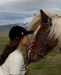 a woman is petting the head of a horse