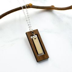 "This rectangular bar necklace offers the boldness of a geometric design combined with the delicacy of a long, slender composition. The outer rectangle encompasses an inner panel for a multi-faceted design with movement and visual interest. Two tones of intricately cut wood - walnut and maple - give additional texture to the piece. Wood and silver necklaces can be dressed up or down, making them the perfect complement to any outfit! Pair with the matching rectangle earrings for a coordinated loo Cricut Wood Necklace, Laser Cut Necklace, Wood Jewelery, Rectangle Necklace, Laser Cut Wood Crafts, Faceted Design, Rectangle Earrings, Earring Ideas, Printed Jewelry