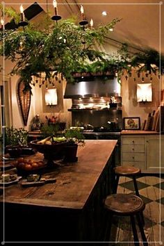 the kitchen is decorated with greenery and hanging lights from the ceiling above the island