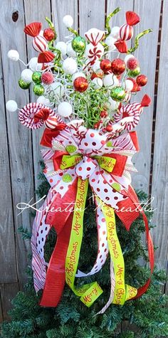 a christmas tree decorated with candy canes and candies in front of a wooden fence