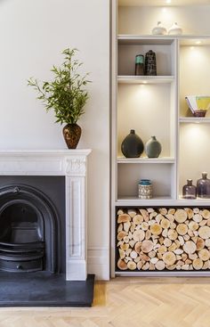 a living room with a fire place and shelves filled with wood logs next to a fireplace