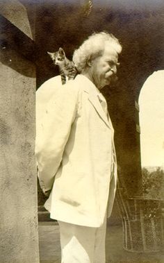 an old black and white photo of a man with a cat on his shoulder looking at him