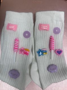 two pairs of white socks with pink and purple toothbrushes on them, next to each other