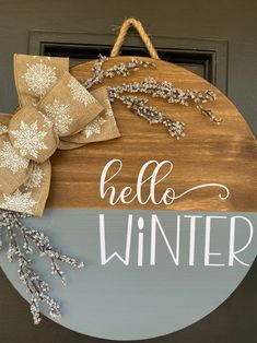 a wooden sign that says hello winter hanging on a door with burlocks and snowflakes