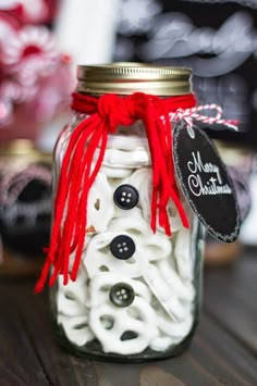 a mason jar filled with white and black macaroni shells covered in red ribbon