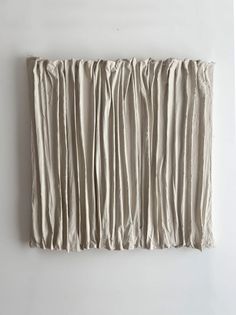 a piece of art that looks like pleated fabric hanging on the side of a wall