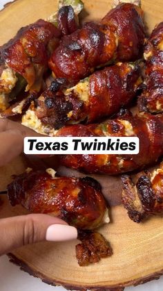 a person pointing at some food on a wooden platter that says texas twinkies