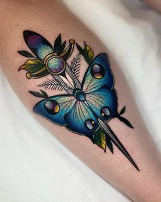 a blue butterfly tattoo on the leg with flowers and leaves around it's wings