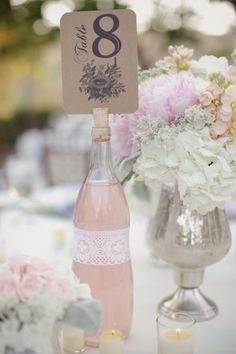 the table numbers are placed on top of bottles and vases with flowers in them