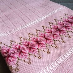 a pink and brown knitted blanket sitting on top of a table