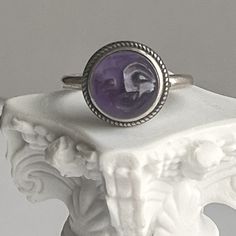 Genuine 10MM carved amethyst cabochon moon face sterling silver adjustable ring. Natural 10MM amethyst cabochon hand carved with smiling face Bezel set in sterling ring shank  Antiqued rope border Adjustable ring measures size 7 but adjustable to 9 comfortably Perfect for men and women This listing is for 1 ring  Thanks for stopping by Adjustable Vintage Sterling Silver Amethyst Ring, Vintage Adjustable Amethyst Ring In Sterling Silver, Bohemian Amethyst Sterling Silver Ring, Nickel Free Lavender Round Jewelry, Adjustable Round Lavender Jewelry, Adjustable Lavender Round Jewelry, Adjustable Lavender Jewelry, Lavender Nickel-free Round Jewelry, Handmade Adjustable Sterling Silver Amethyst Ring