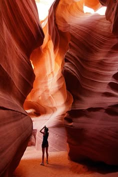 a woman standing in the middle of a narrow canyon