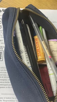 pencils, pens and markers are in a zippered pouch on top of a piece of paper