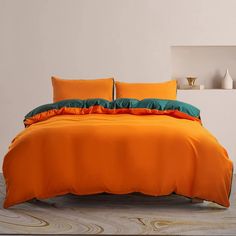 an orange bed with two pillows on it and a green pillow case in the corner