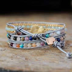 three bracelets with different colored beads and gold accents on top of a wooden table