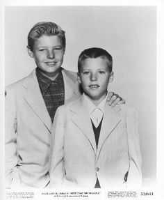 an old photo of two young men posing for a picture in front of a white background