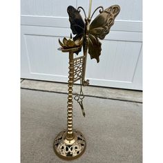 a metal butterfly decoration on top of a stand in front of a garage door,