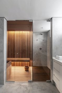 a wooden sauna in the middle of a bathroom with a glass shower stall and sink