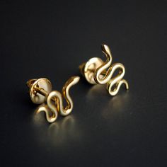 two pairs of gold earrings on a black surface