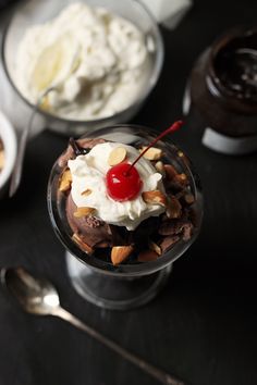 an ice cream sundae with chocolate pudding, nuts and cherries on the side